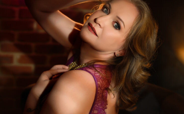 Boudoir portrait in magenta lace against an exposed brick wall