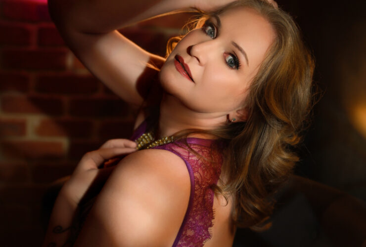 Boudoir portrait in magenta lace against an exposed brick wall