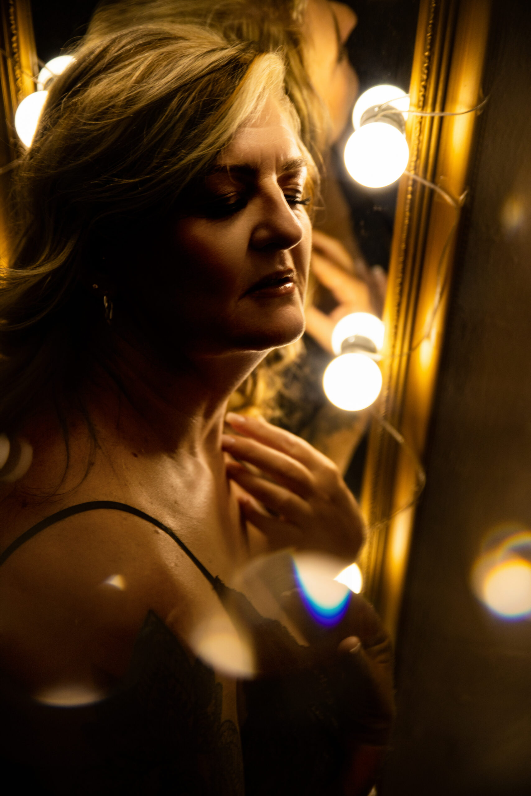 Woman glowing beside a vanity mirror, boudoir photography Melbourne